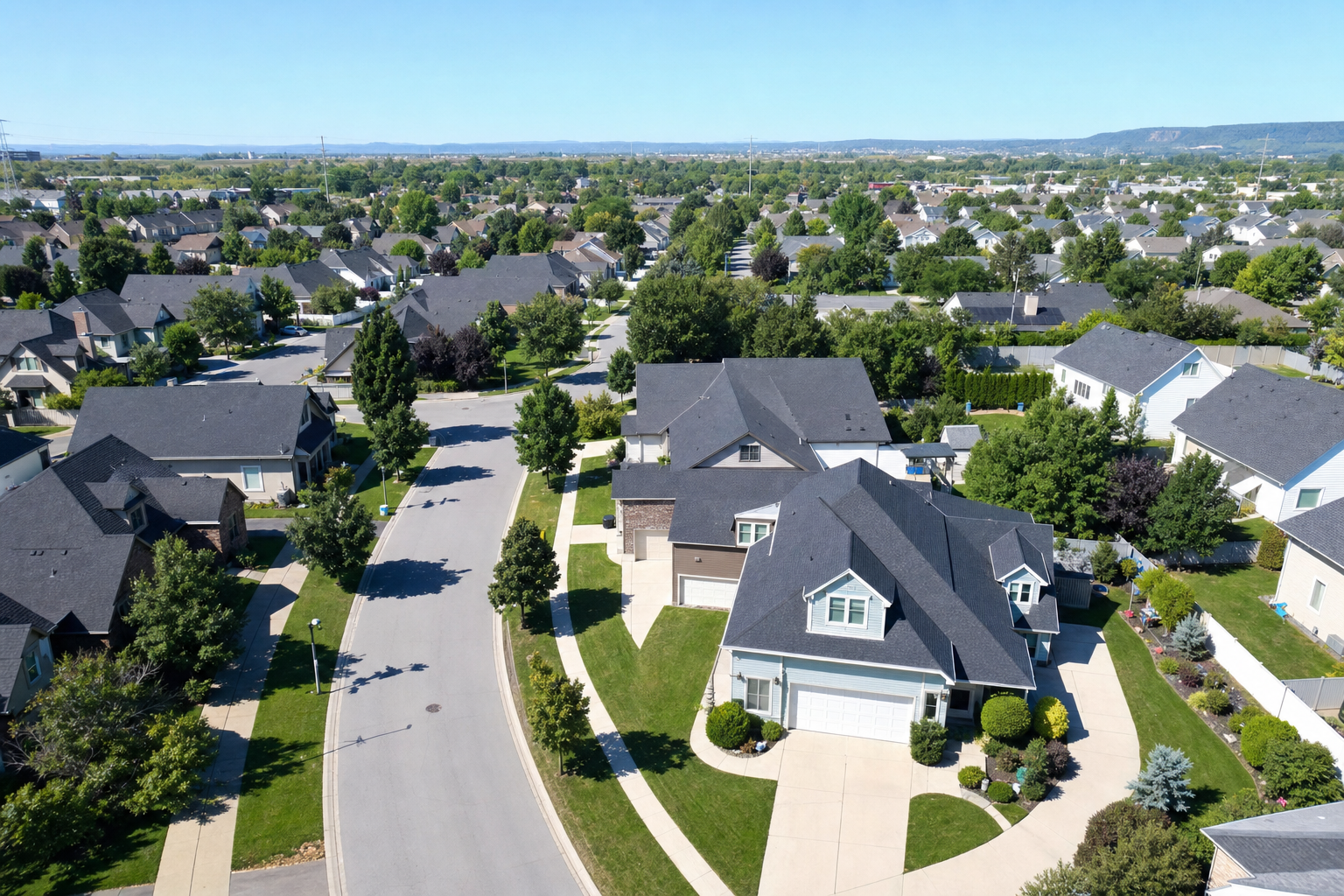 Aerial view of a residential neighborhood with pitched shingle roofs, representative of the roofing and construction industry in this story